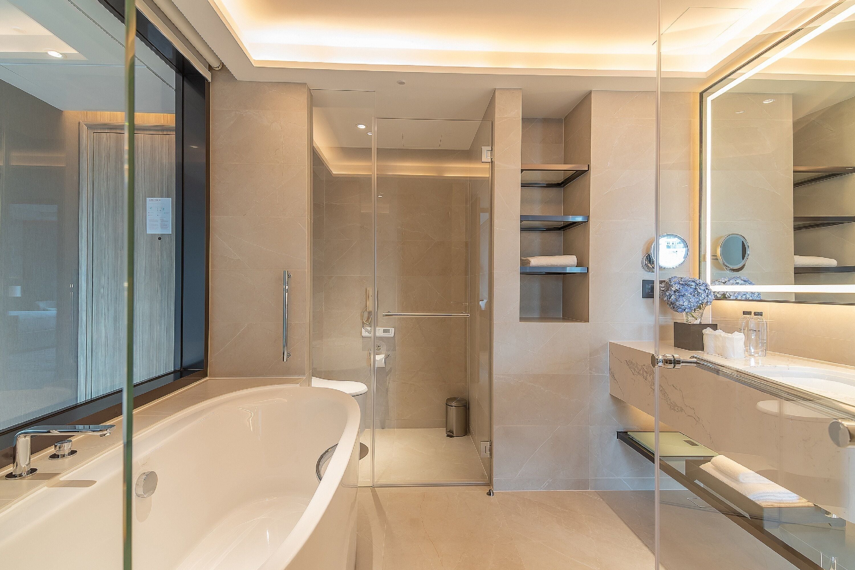 A modern bathroom with a glass-enclosed shower, a large bathtub, and a vanity with a mirror.