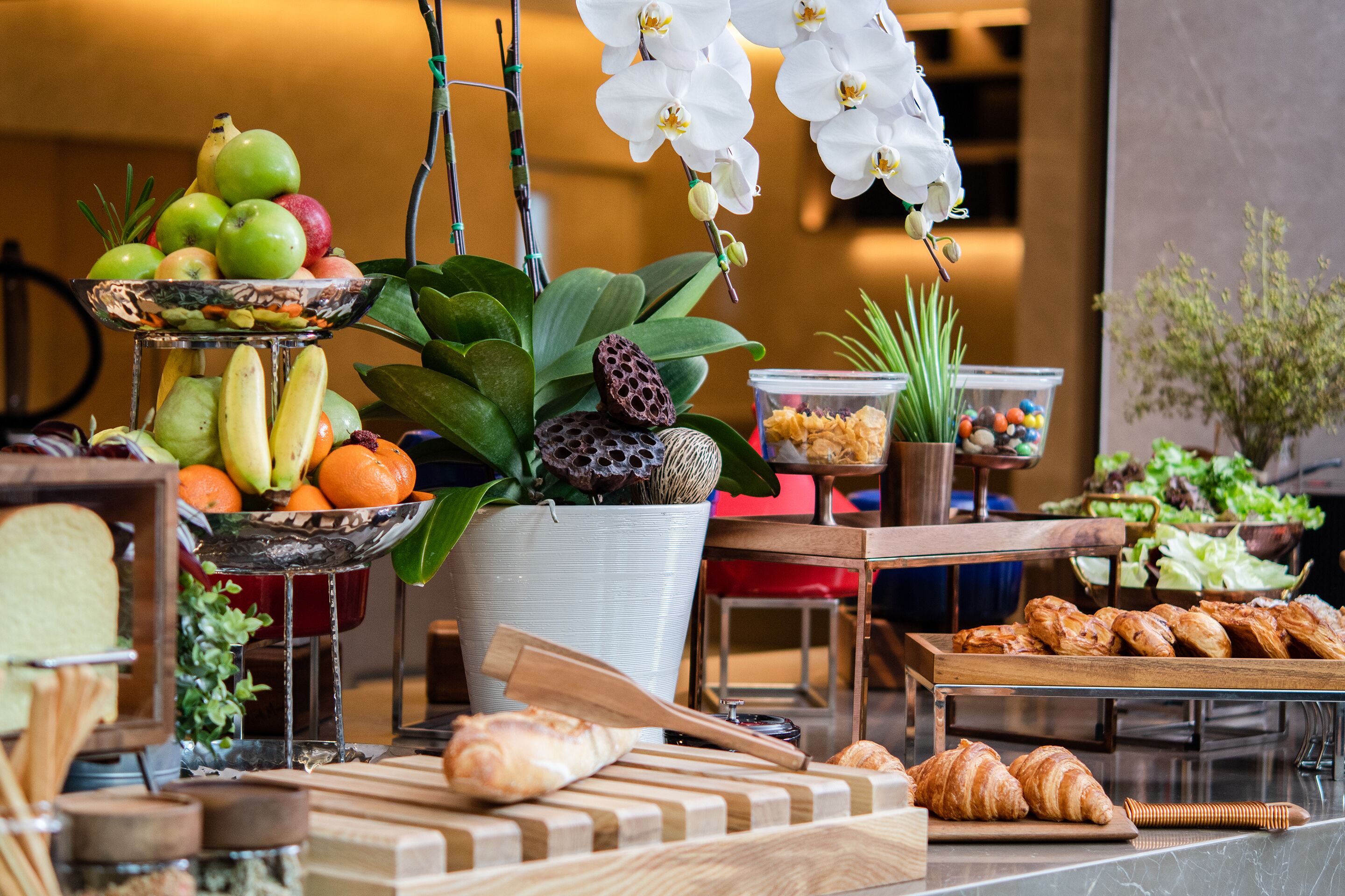 A breakfast buffet with fruits, pastries, and flowers.