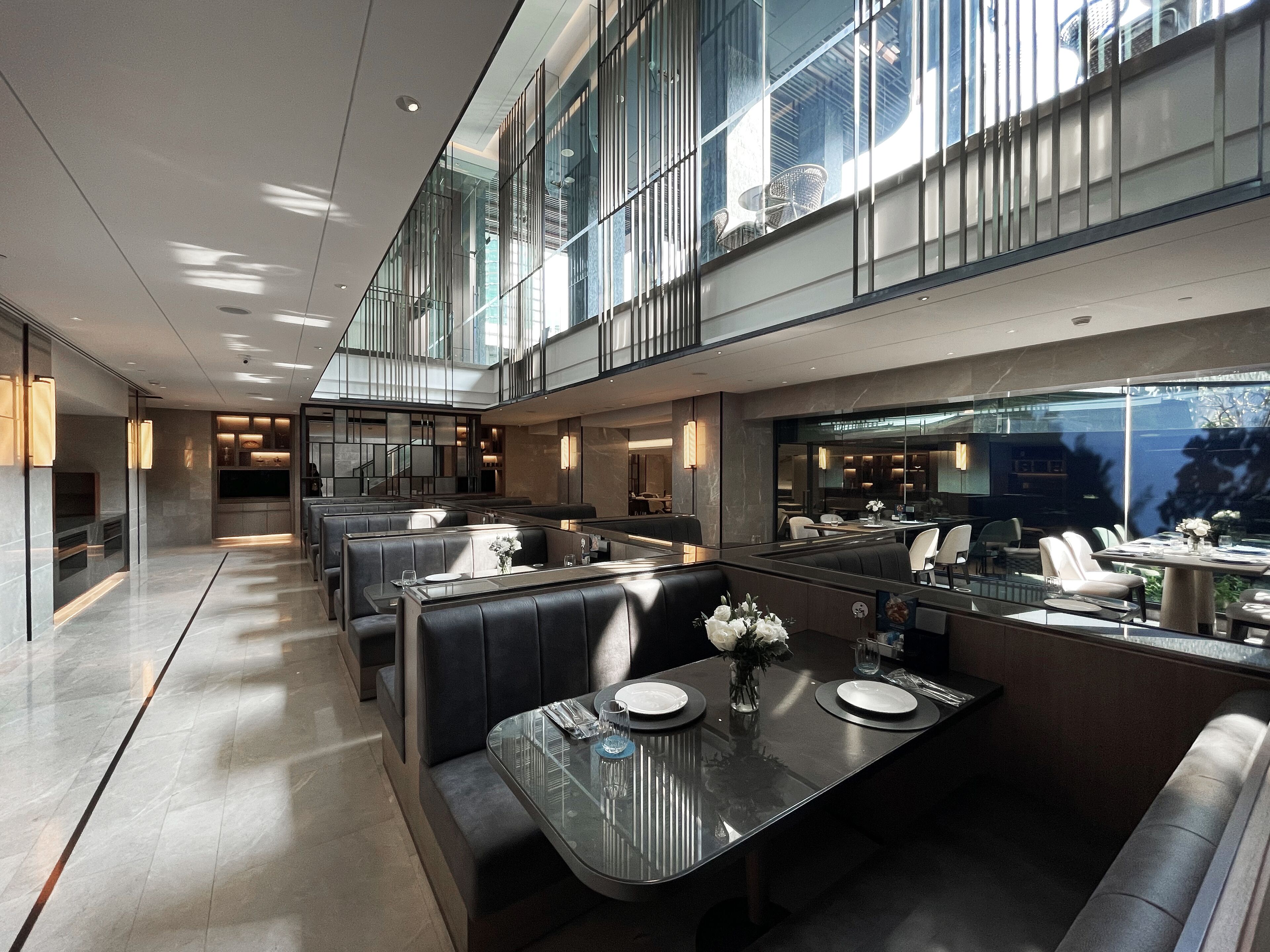 A modern dining area with glass partitions, leather seating, and a view of the outdoors.