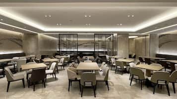 Un restaurante moderno con varias mesas y sillas, una pared decorativa central e iluminación empotrada.
