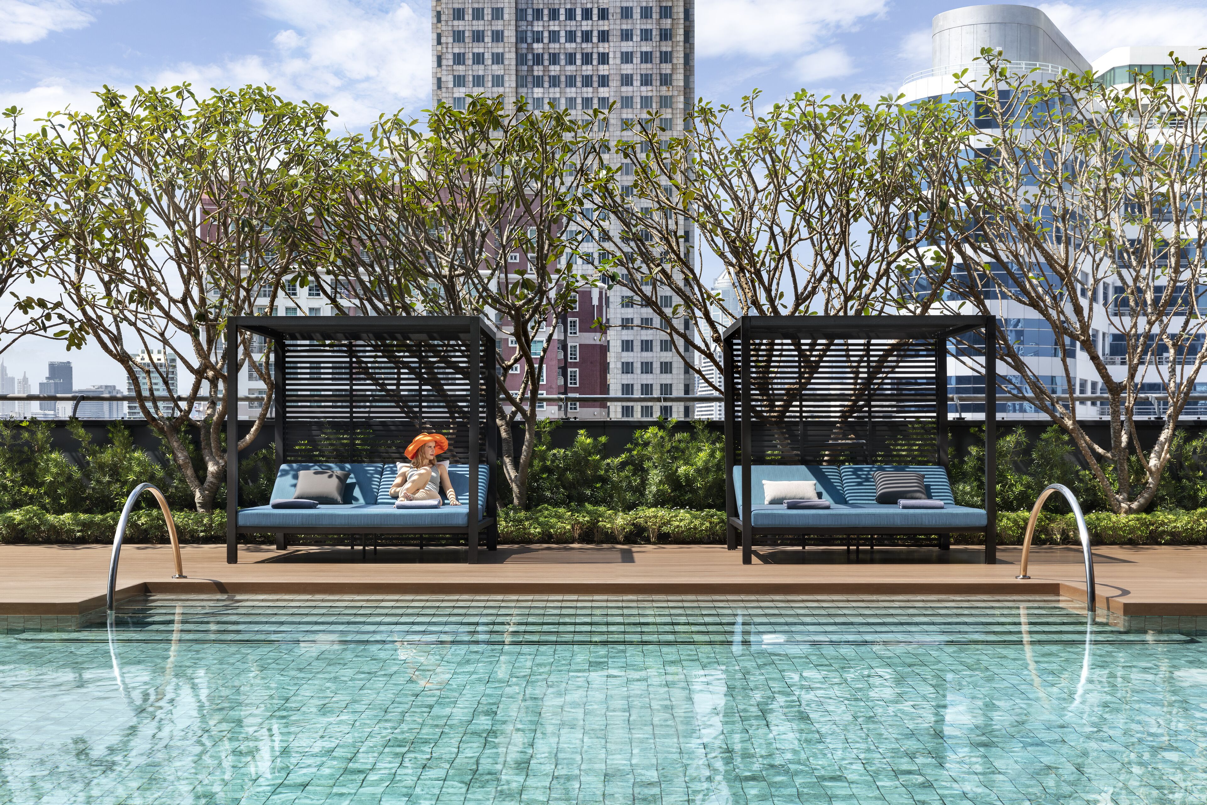 A rooftop pool area with two lounge chairs and a view of the city skyline.