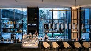 Un moderno bar con mostrador, asientos y una vitrina de pasteles.