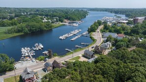 An aerial view of a marina with boats docked, surrounded by lush greenery and residential buildings.
