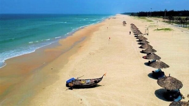 A beach with a row of thatched umbrellas and a boat on the sand. - Ba Co Boutique Hotel (Da Nang)