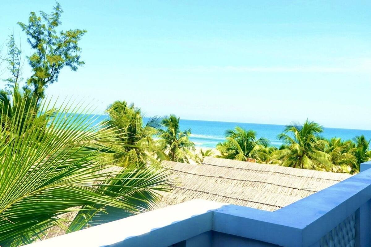 Ein Balkon mit Blick auf das Meer und Palmen.