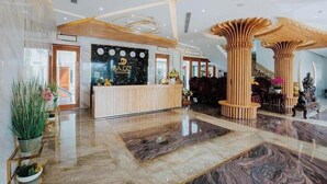 A hotel lobby with a reception desk, wooden columns, and a marble floor. - Ba Co Boutique Hotel (Da Nang)