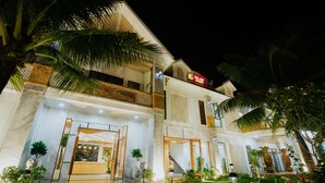 A two-story hotel with a well-lit entrance, a visible reception desk, and a landscaped garden area. - Ba Co Boutique Hotel (Da Nang)