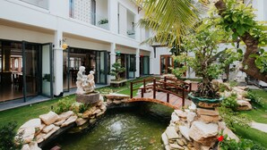 A courtyard with a small bridge, a pond, and a statue. - Ba Co Boutique Hotel (Da Nang)