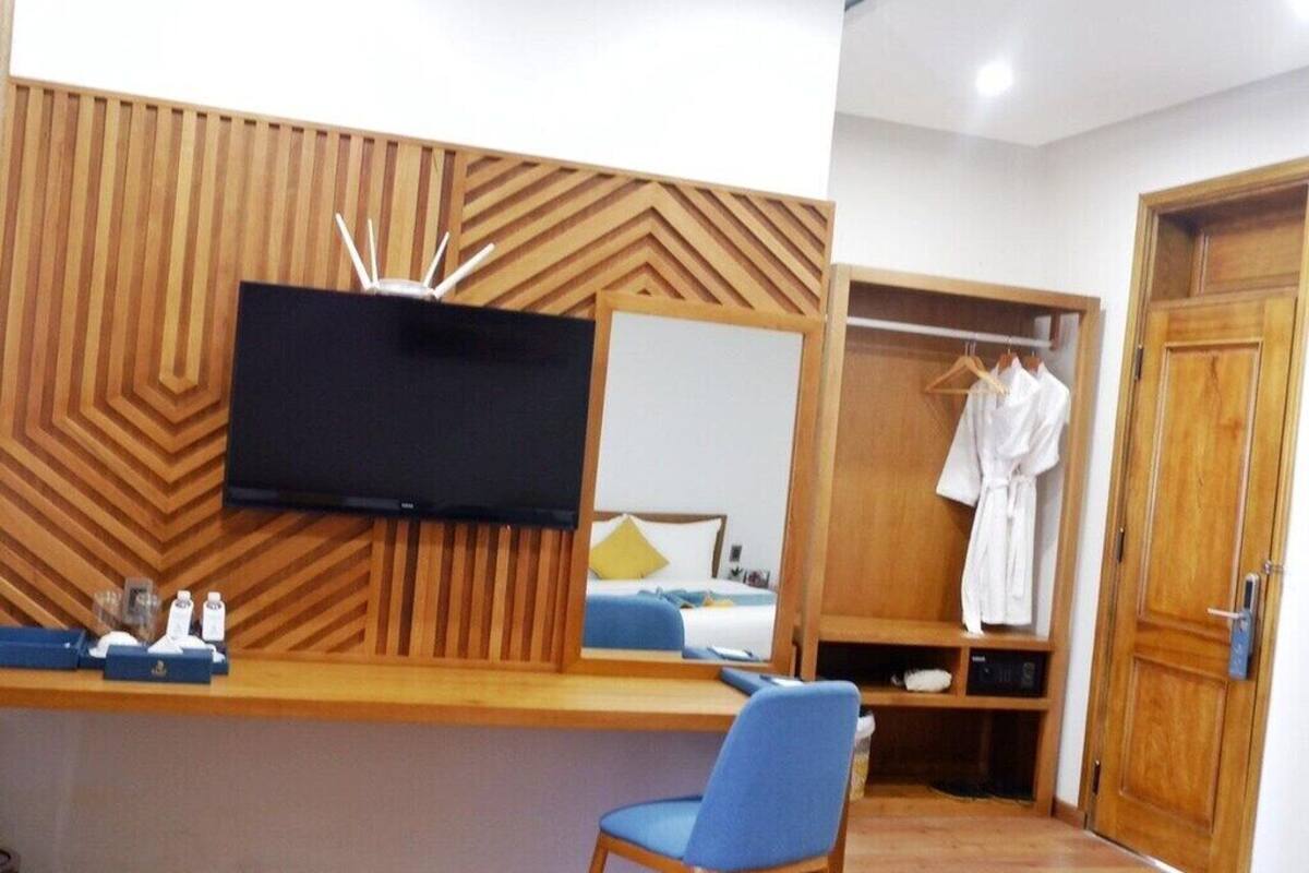 Ein Hotelzimmer mit Holzpaneelen, einem Flachbildfernseher, einem blauen Sessel, einem Kleiderschrank und einem aufgehängten Bademantel.