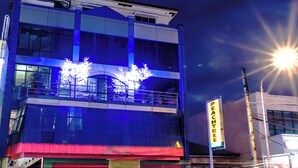 Un edificio de varios pisos con fachada de vidrio y un toldo rojo al nivel de la calle.