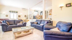 A spacious living room with two dark leather sofas, a glass coffee table, and a staircase leading to an upper floor. - Gorgeous home in Trullent (Trullent)