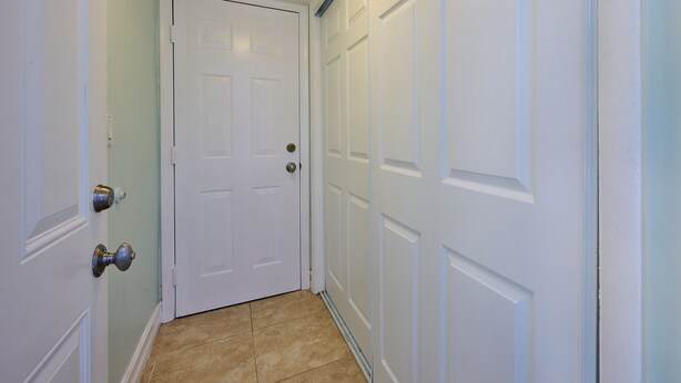A hallway with white doors, a light switch, and a doorbell. -  Beach getaway 1 bdrm, private patio! STEPS TO BEACH! Summer Sale! (Boca Raton)