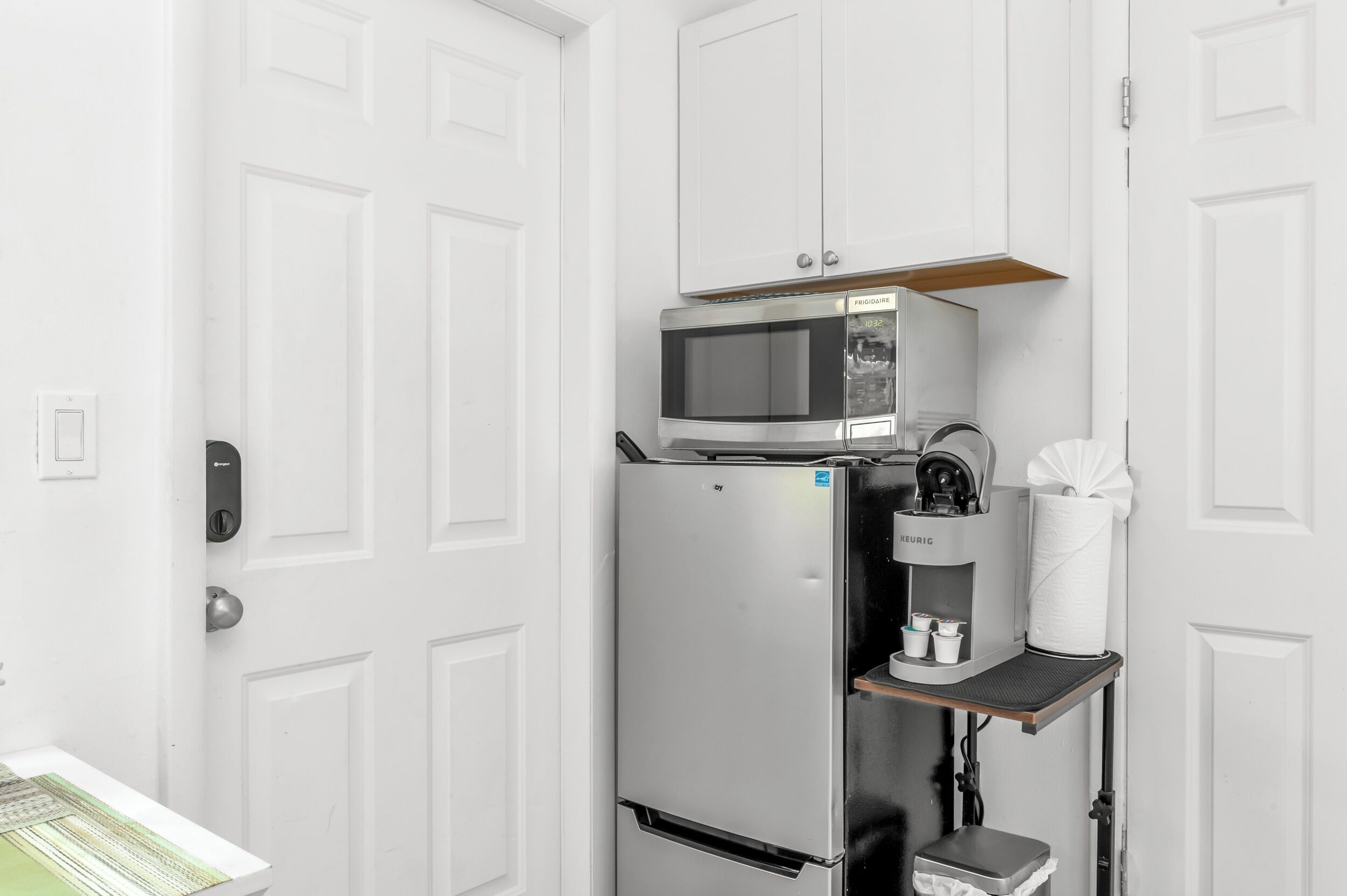 Una kitchenette funcional con microondas, cafetera y refrigerador pequeño.