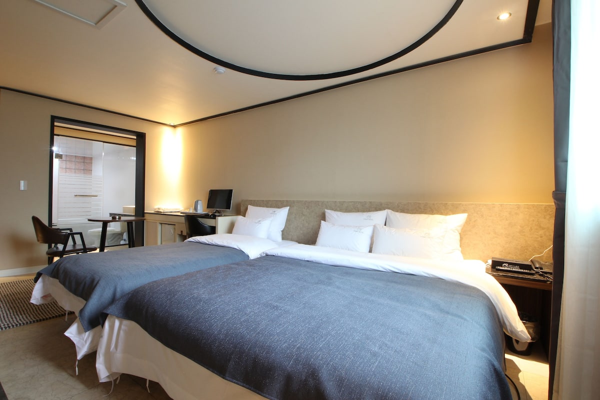 Ett hotellrum med två sängar, ett skrivbord och en stol.