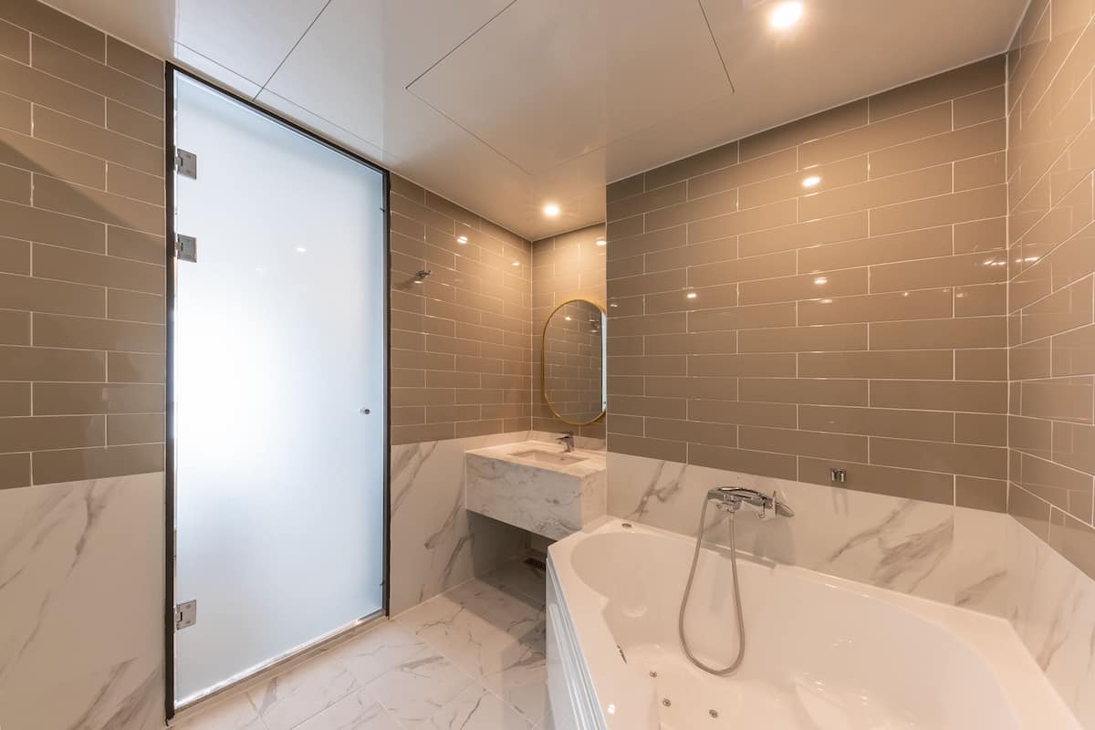 Une salle de bain moderne avec une porte de douche en verre, un lavabo en marbre et une baignoire sur pieds.