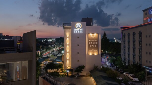 Een modern hotel met een opvallend bord waarop staat dat het feestelijk wordt geopend.