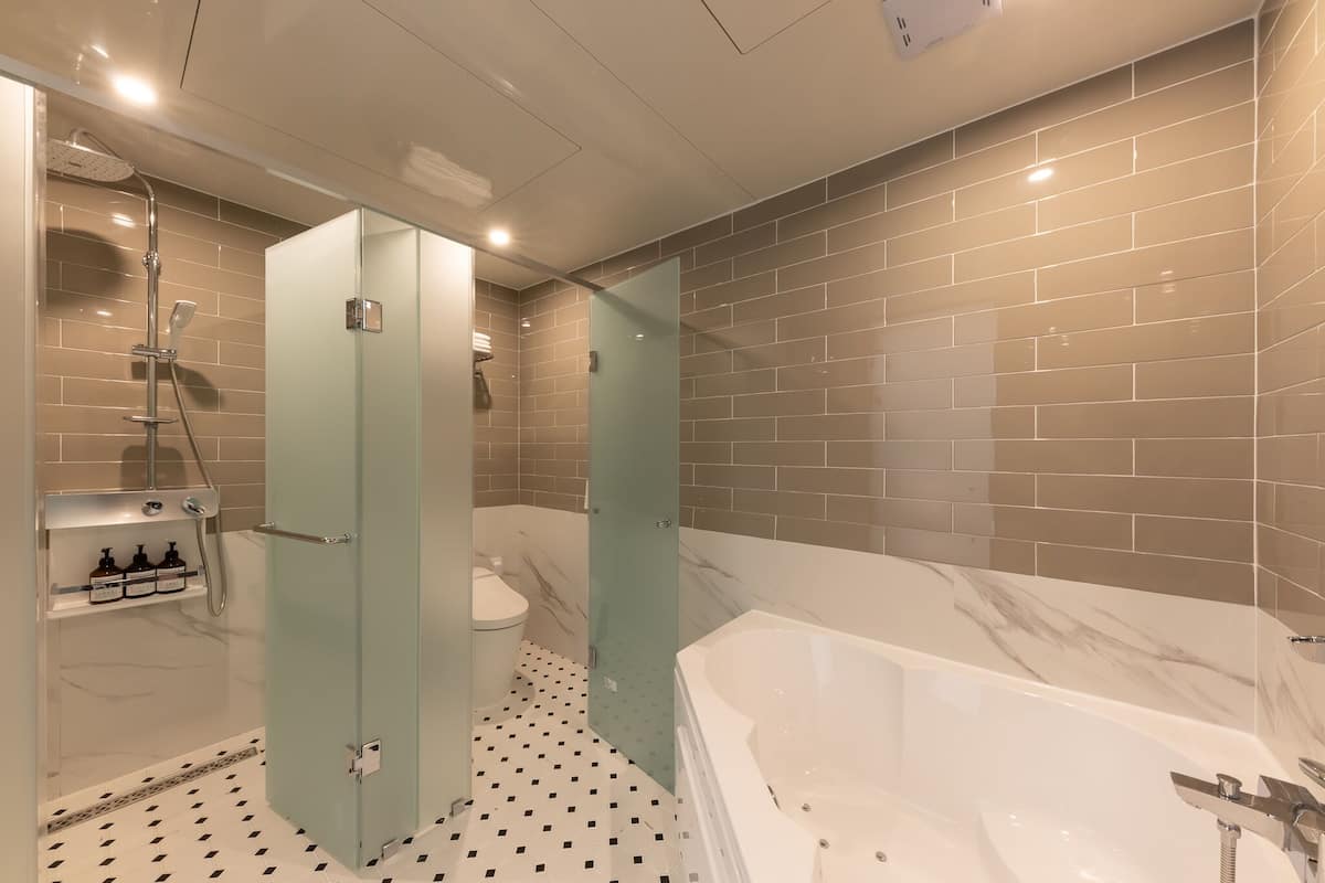 Une salle de bain moderne avec une douche à parois de verre, une baignoire blanche et des toilettes.
