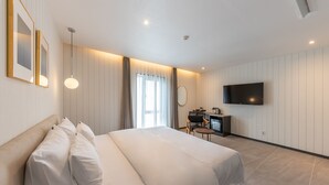 Een hotelkamer met een groot bed, een bureau met stoel, een televisie en een raam met gordijnen.