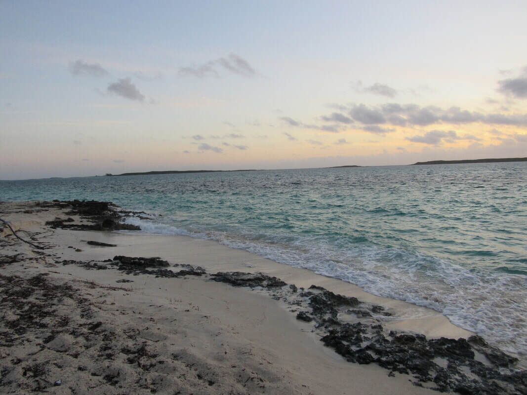Une plage bordée d’une côte rocheuse et baignée par une mer calme.