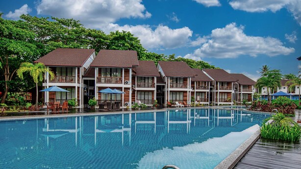 A hotel with a swimming pool, multiple balconies, and outdoor seating areas. - Borneo Divers Mabul Resort (Mabul Island)
