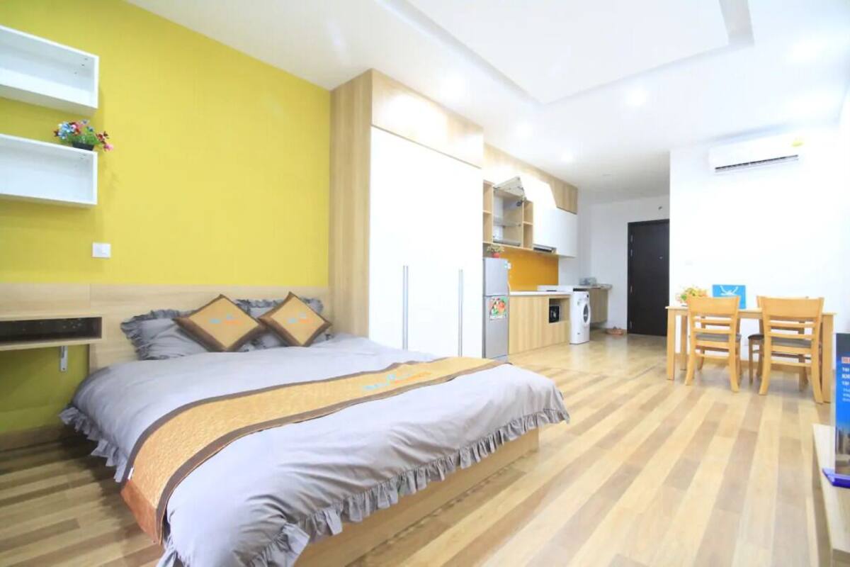 Een kleine hotelkamer met een bed, een kitchenette en een eethoek.