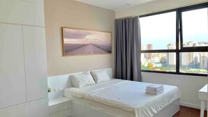 Ein modernes Schlafzimmer mit einem großen Bett, Blick auf die Stadt durch ein Fenster und einem Gemälde an der Wand.
