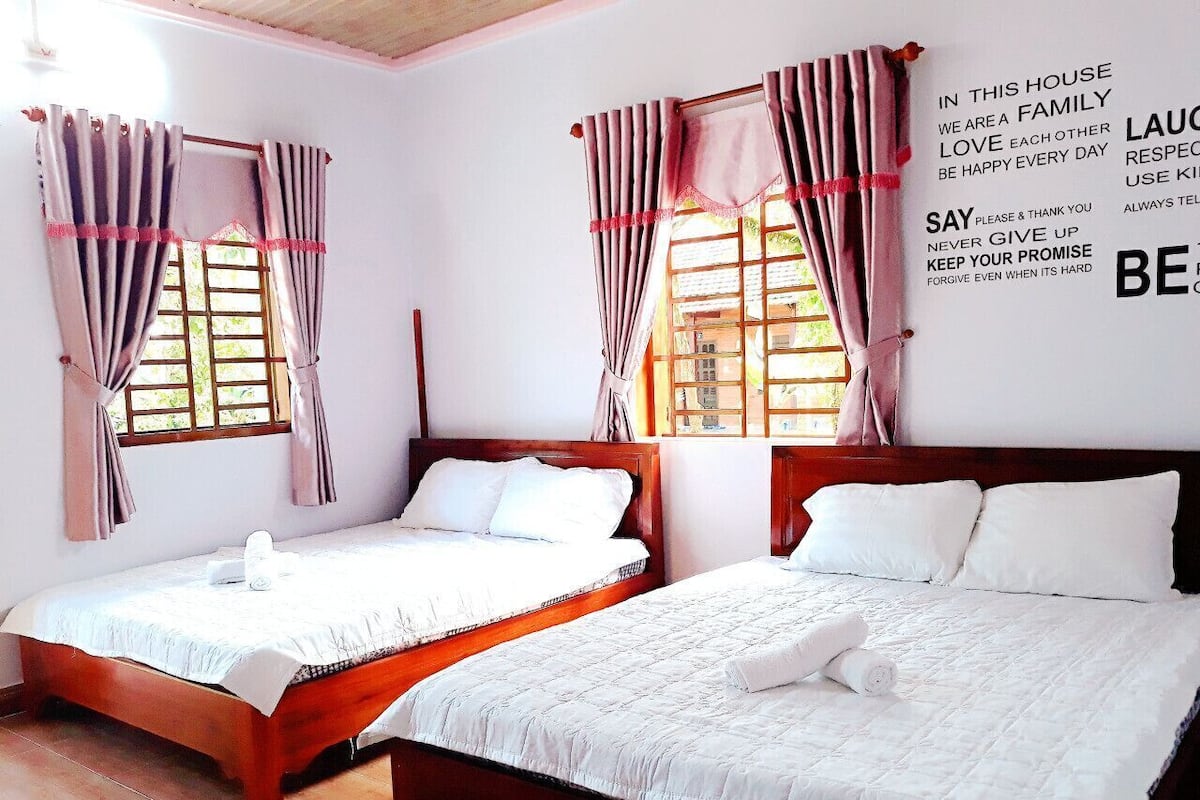 A bedroom with two beds, wooden headboards, and a wall with motivational quotes.