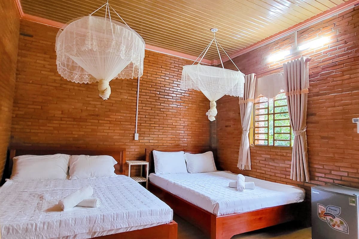 A room with two beds, a small table, and a refrigerator.