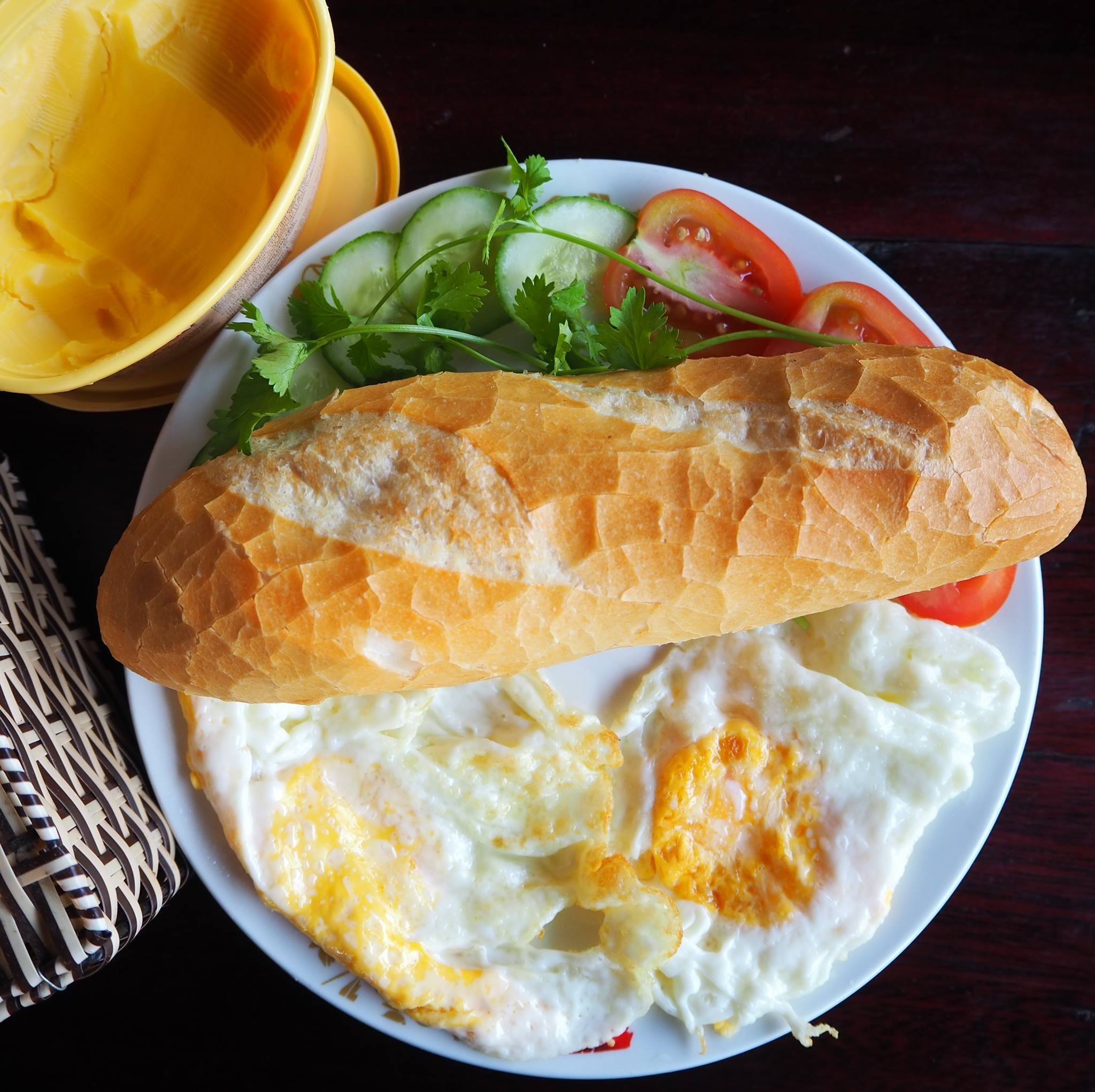 A plate with a baguette, fried eggs, and a salad.