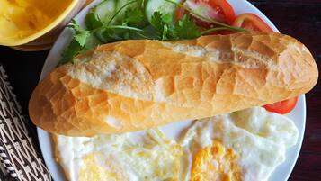 A plate with a baguette, fried eggs, and a salad.