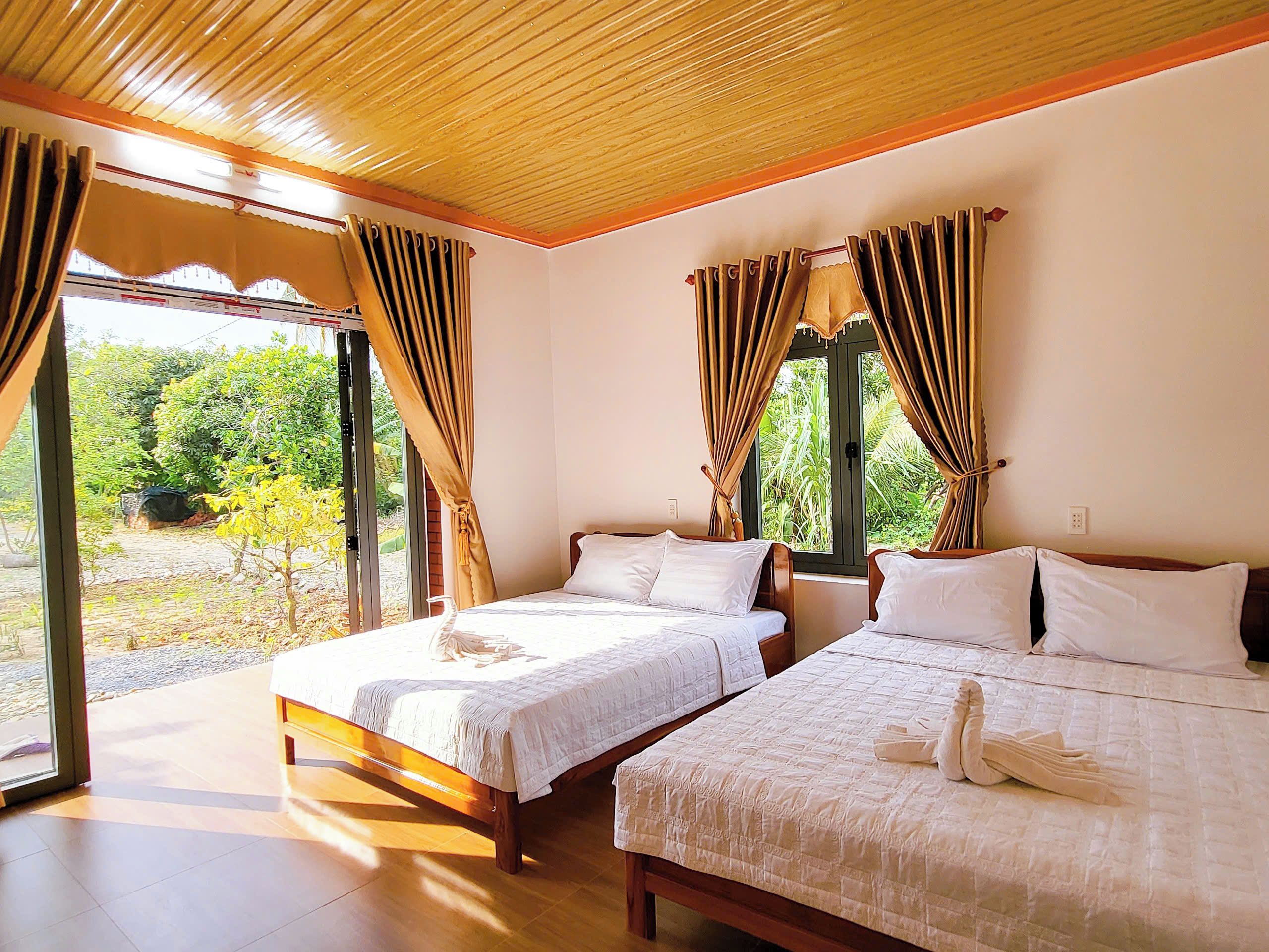 Ein Zimmer mit zwei Betten, Holzboden und Blick auf Grün.