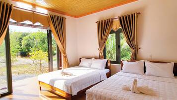 Ein Zimmer mit zwei Betten, Holzboden und Blick auf Grün.
