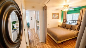 A bedroom with a bed, a ceiling fan, and a view of the kitchen. - End of Summer Savings by the beach at Green Door! (San Diego)