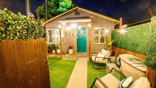 A small house with a green door, a wooden fence, and a lawn. There are chairs and a barbecue grill outside. - End of Summer Savings by the beach at Green Door! (San Diego)