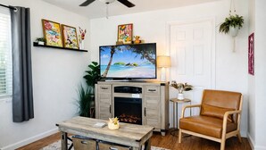 A living room with a television, a fireplace, a brown leather chair, and a coffee table. - End of Summer Savings by the beach at Green Door! (San Diego)
