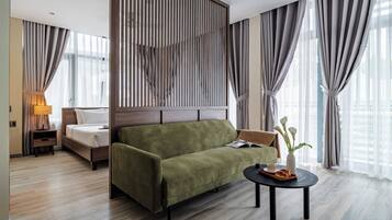 Een moderne hotelkamer met een groene bank, een houten hoofdbord, een klein tafeltje met dienblad en een lamp.