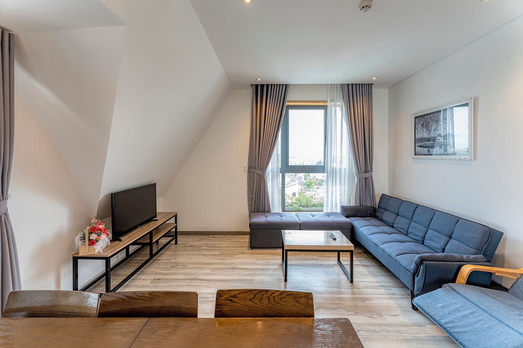 Ein modernes Wohnzimmer mit Flachbildfernseher, einer Couch, einem Couchtisch und einer Holzbank.
