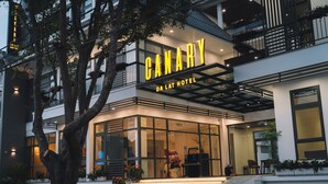 Exterior del hotel Canary Da Lat, con un diseño moderno, amplios ventanales de vidrio y una entrada destacada con escalones.