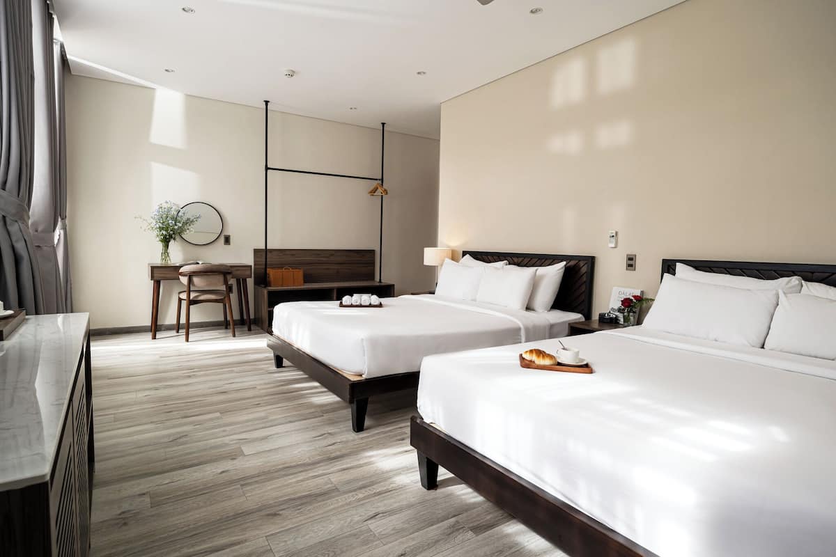 Habitación de hotel con dos camas, un escritorio, una silla y un espejo.