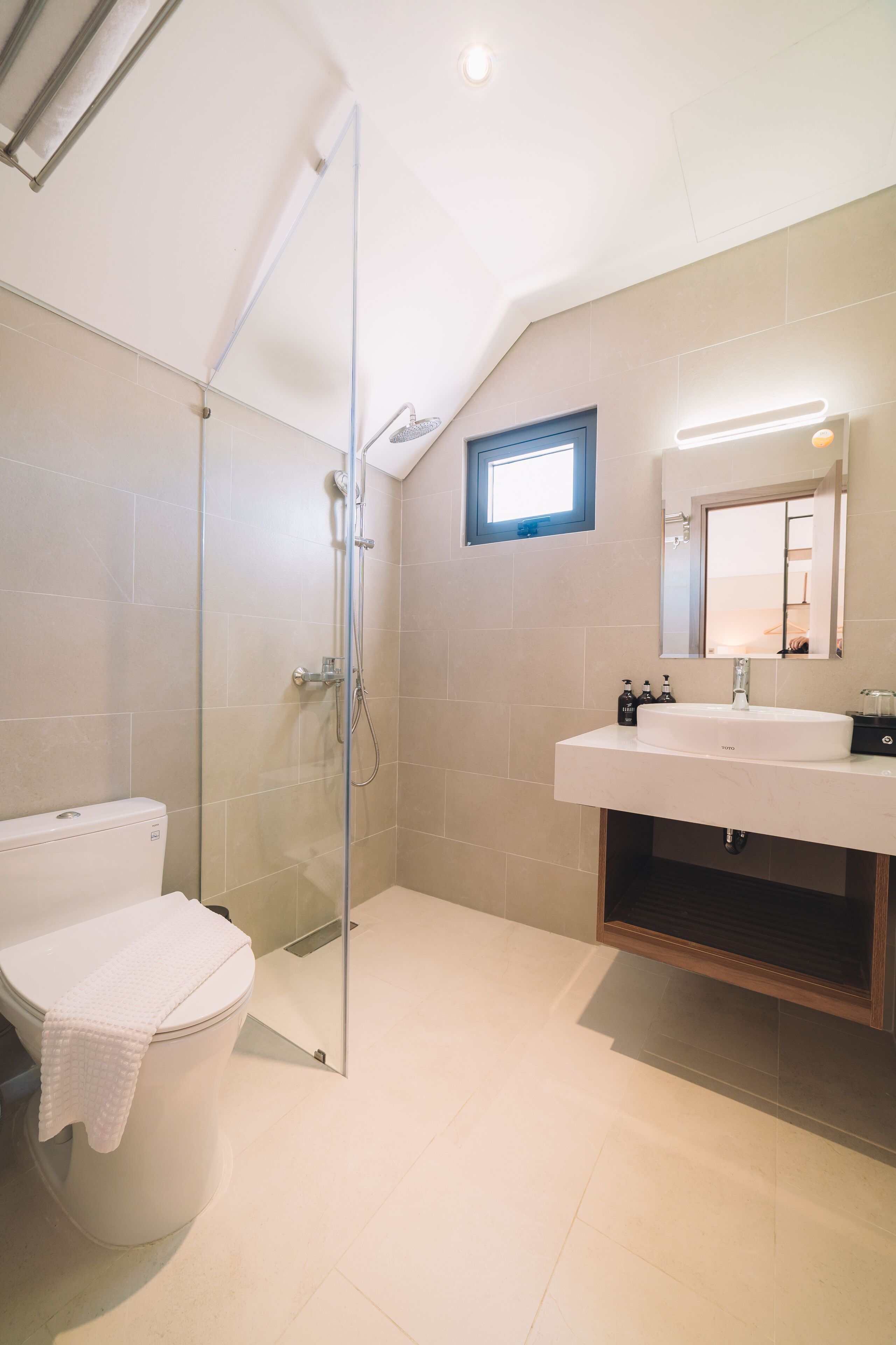 A modern bathroom with a glass-enclosed shower, a white sink, and a mirror above it.