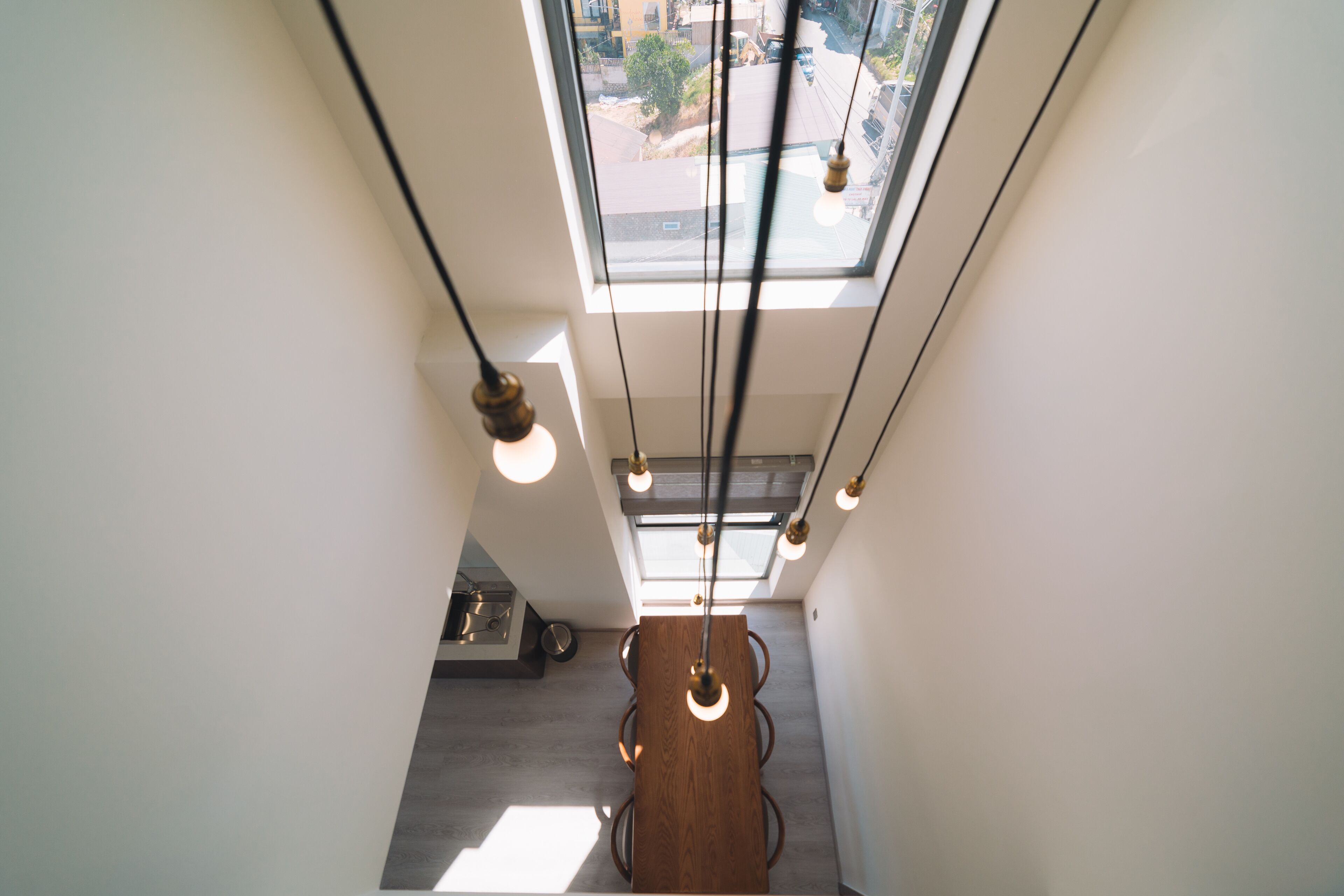 A modern interior with a skylight, pendant lights, and a dining area.