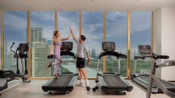 A gym with treadmills, a cityscape view, and a large window.