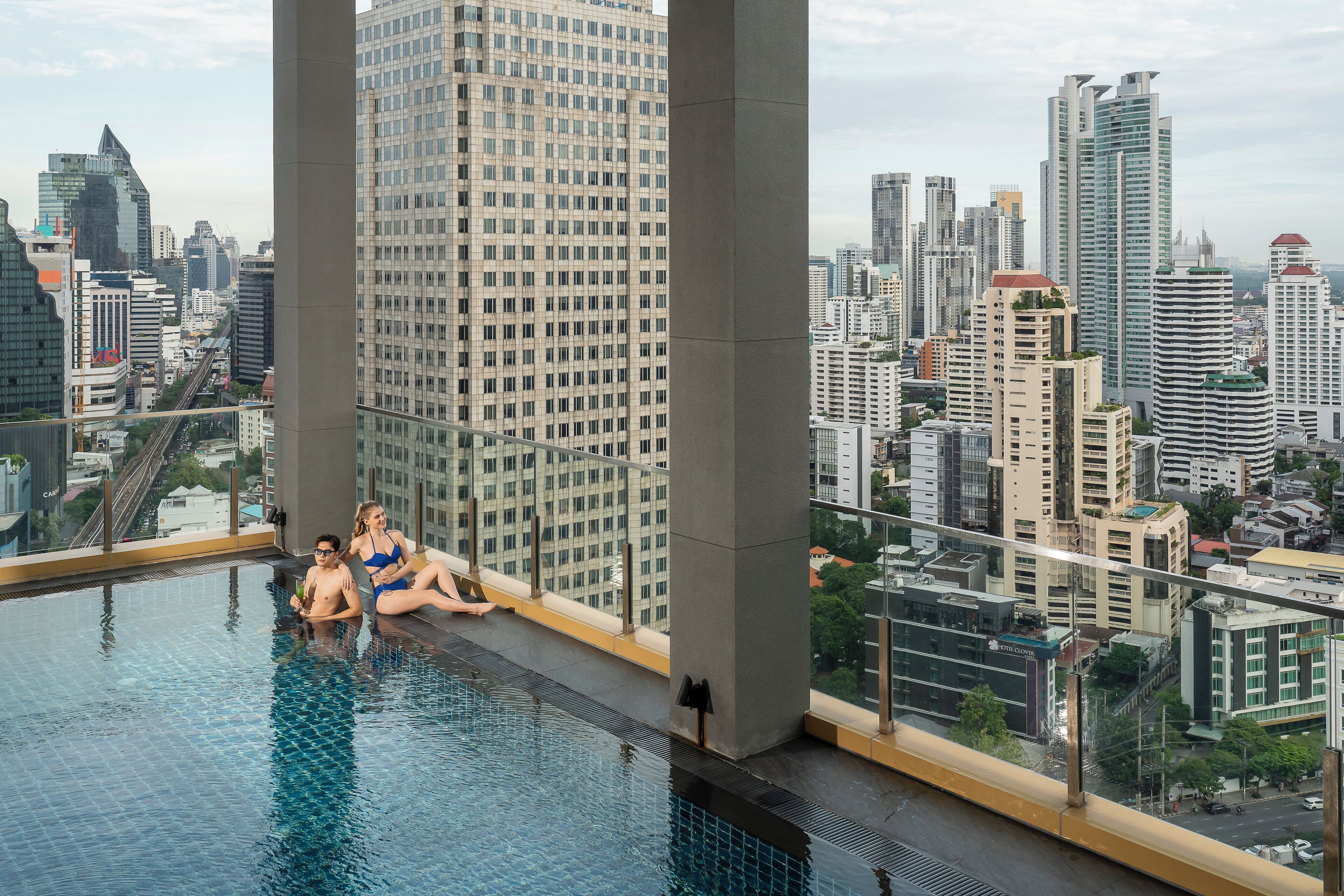 Ein Infinity-Pool auf dem Dach mit Blick auf die Stadt, großen Säulen und einer modernen Architektur.