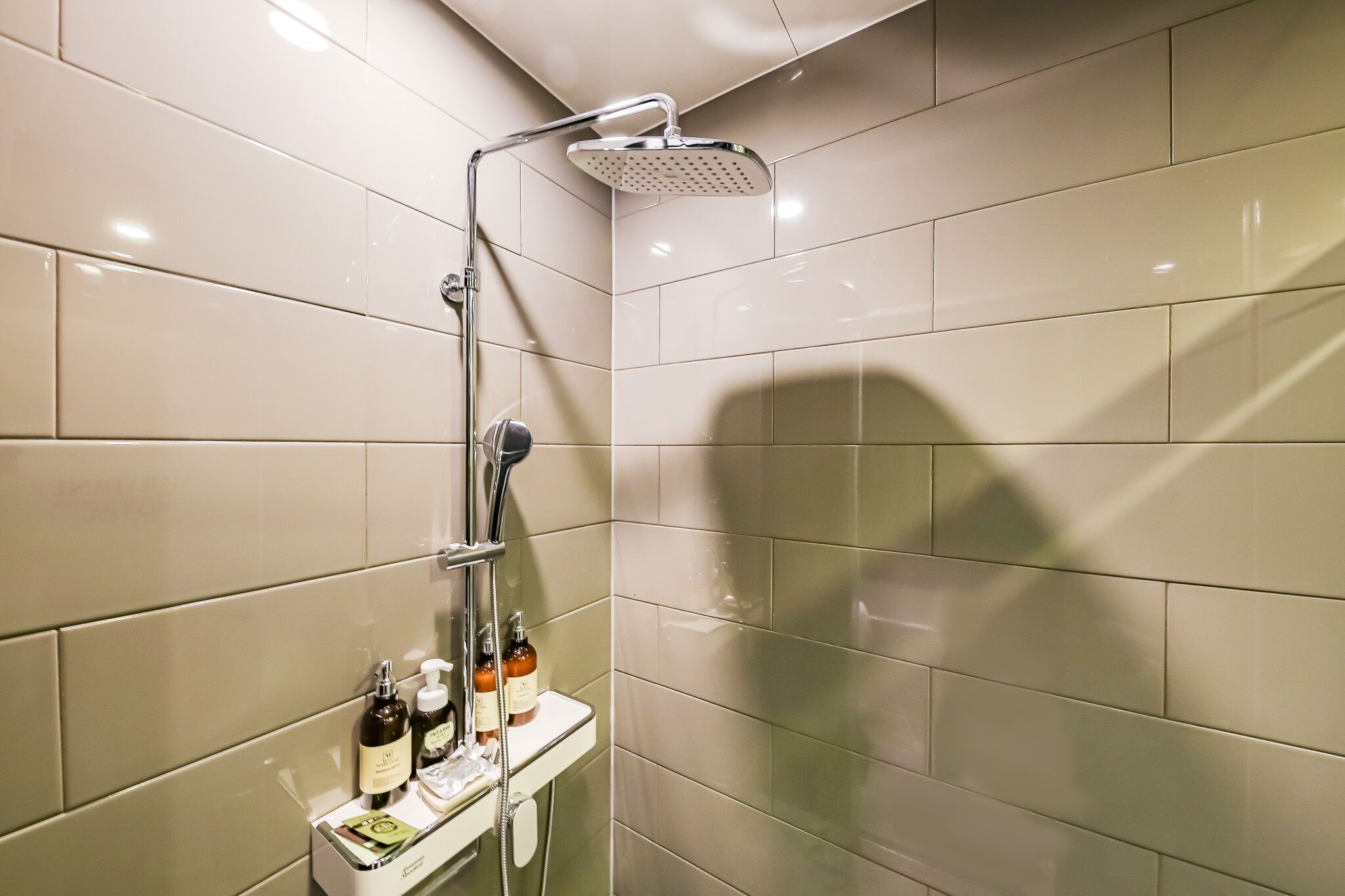 A modern bathroom with a glass-enclosed shower, a vanity with toiletries, and a tiled wall.