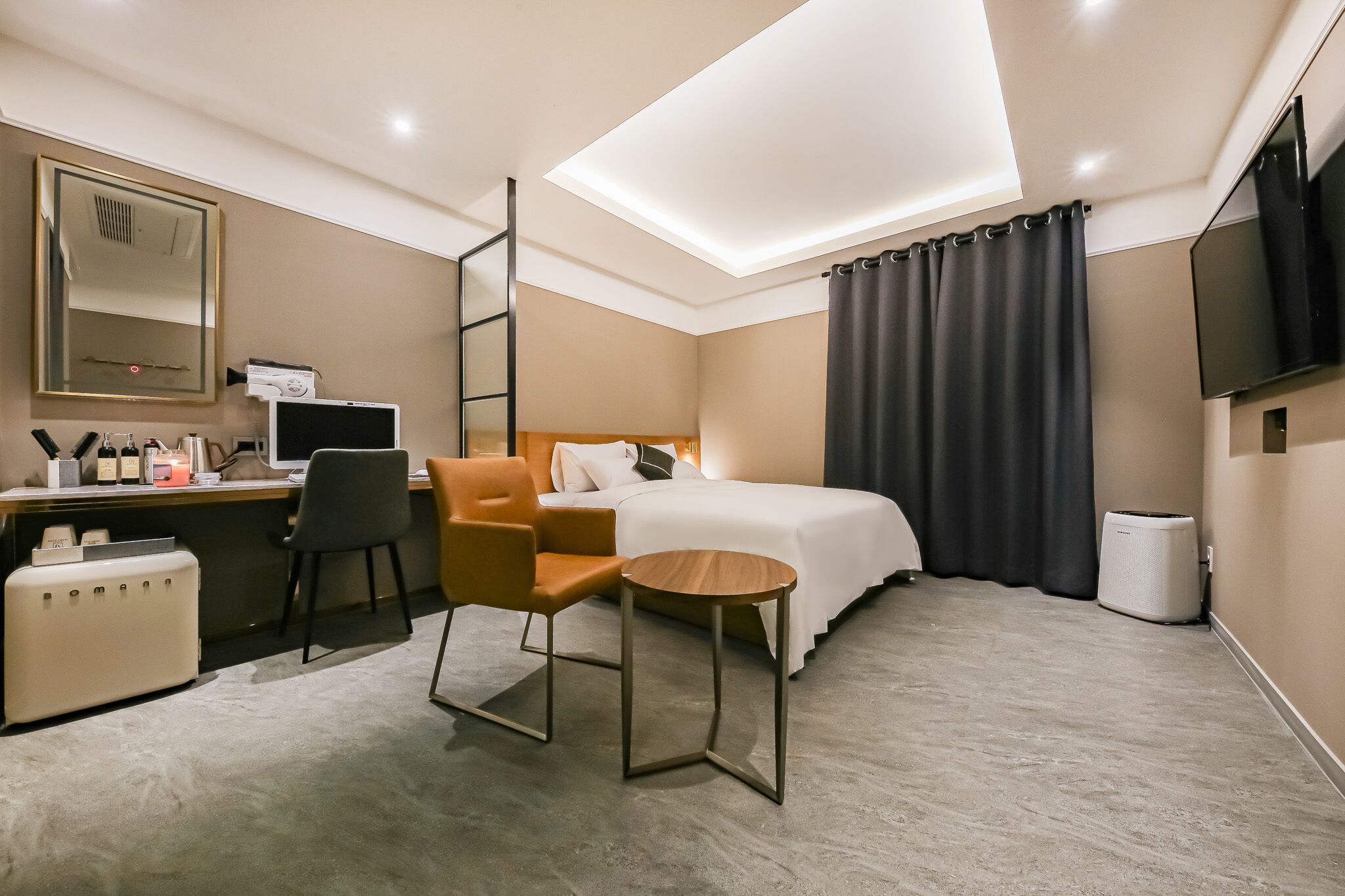 A hotel room with a bed, desk, chair, and a small table.