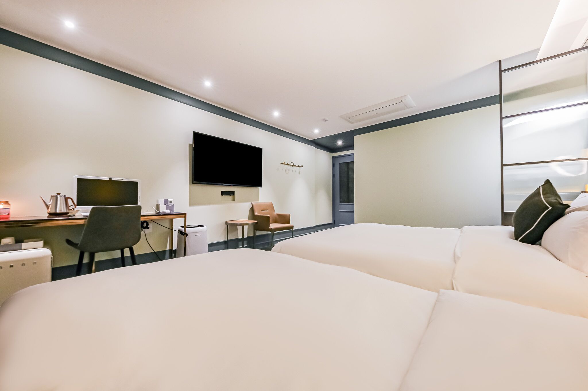 Une chambre d’hôtel avec deux lits, un bureau, une chaise, une télévision et un miroir.