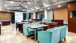 Un restaurante moderno con asientos tapizados en tonos aguamarina y borgoña, piso a cuadros y techo curvo con iluminación empotrada.
