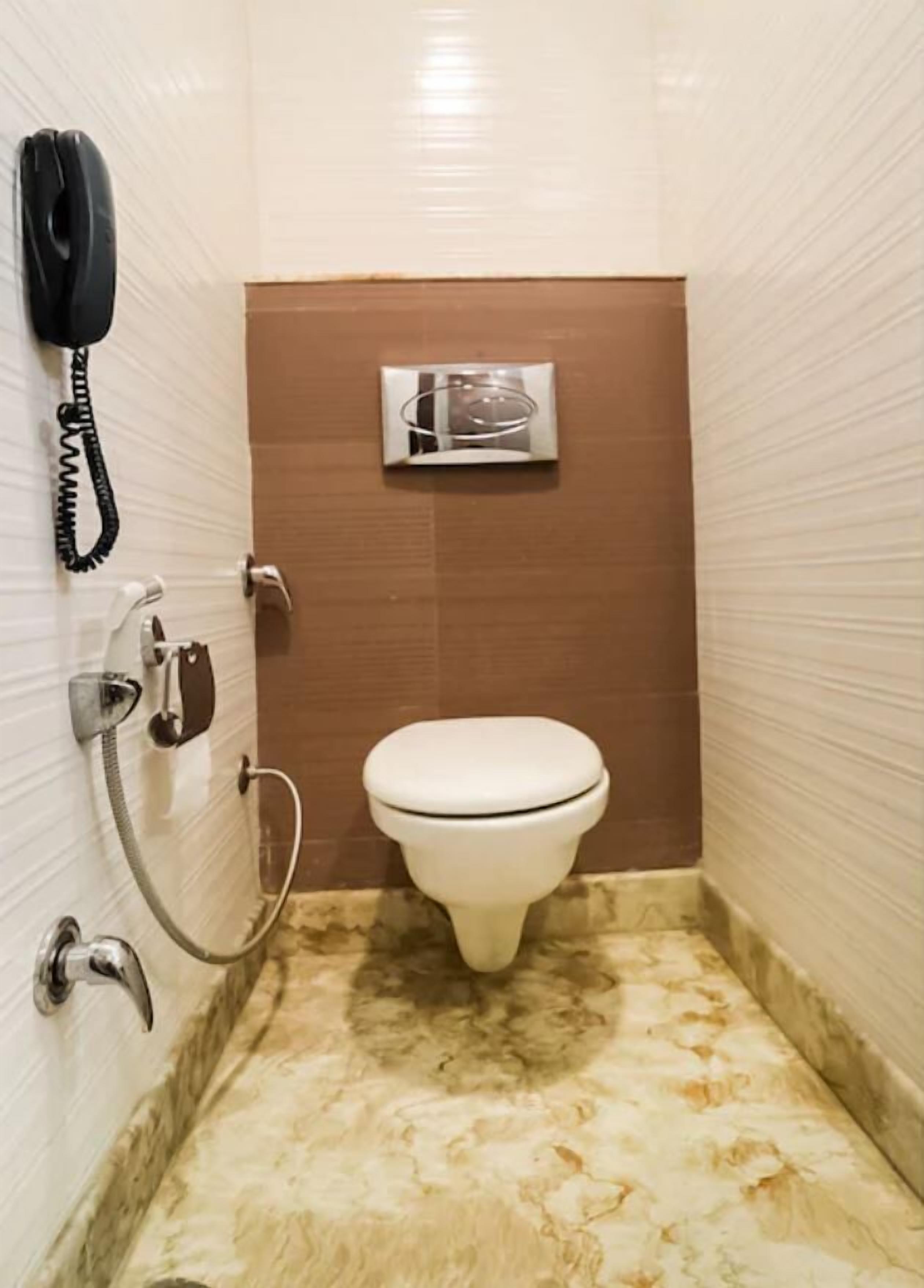 Un baño pequeño con inodoro, secamanos y teléfono.