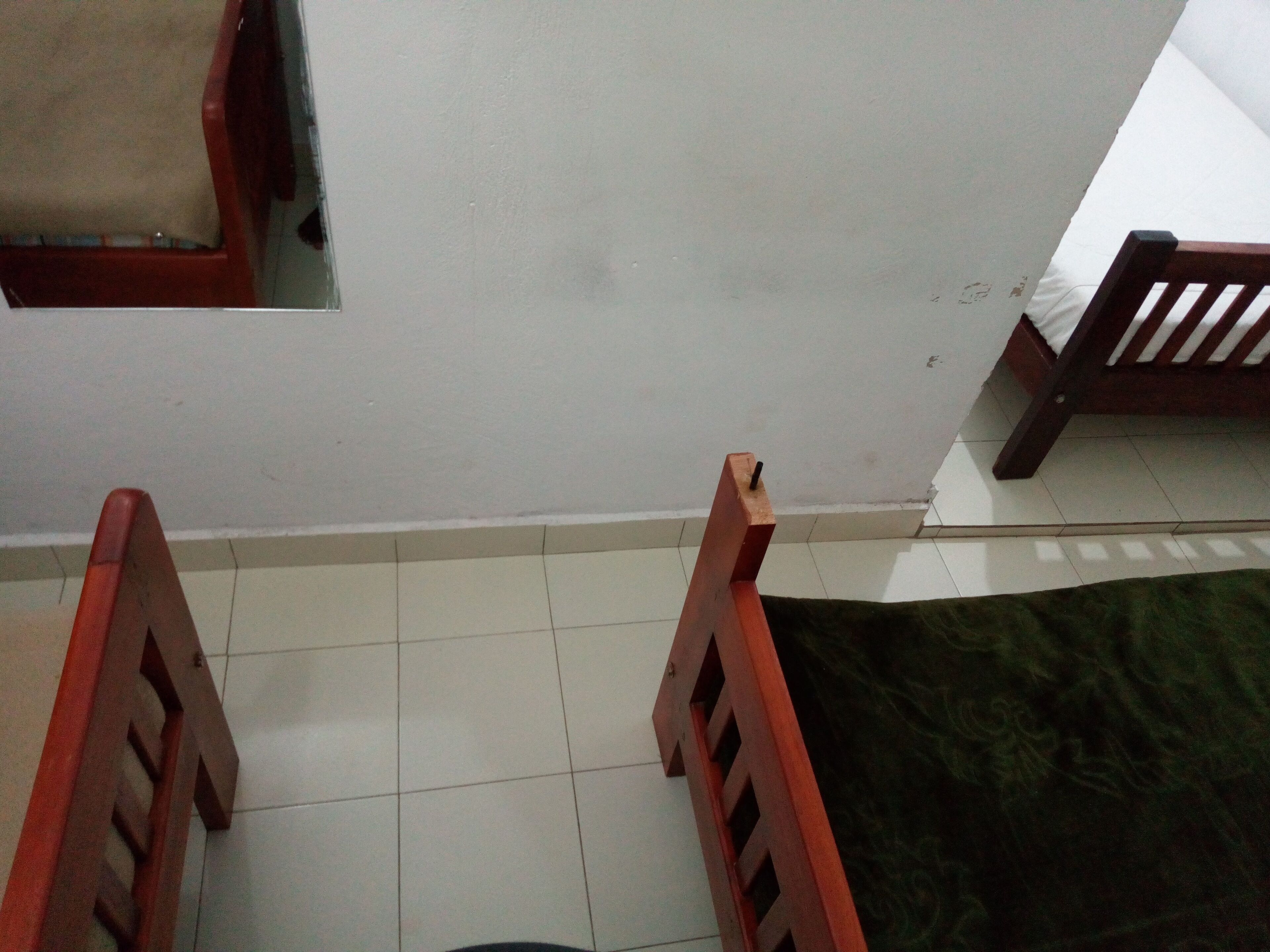 A room with a tiled floor, a green rug, and wooden furniture.