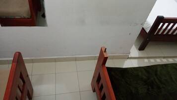 A room with a tiled floor, a green rug, and wooden furniture.